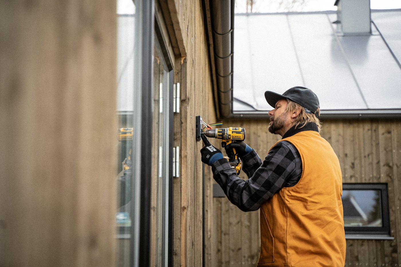 An electrician drilling into a wall during an installation