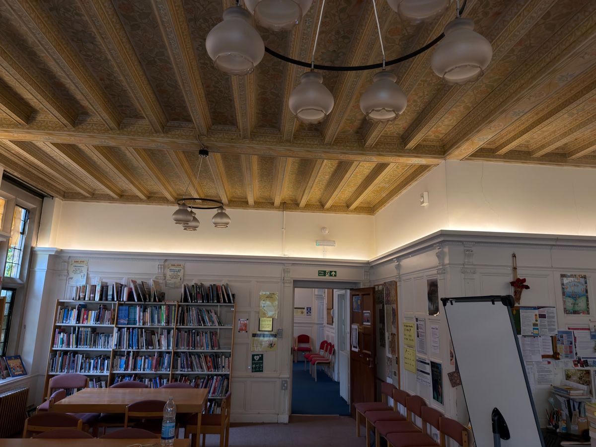 Warm LED uplighting along the top of the panelling, lighting the walls and the painted ceiling above