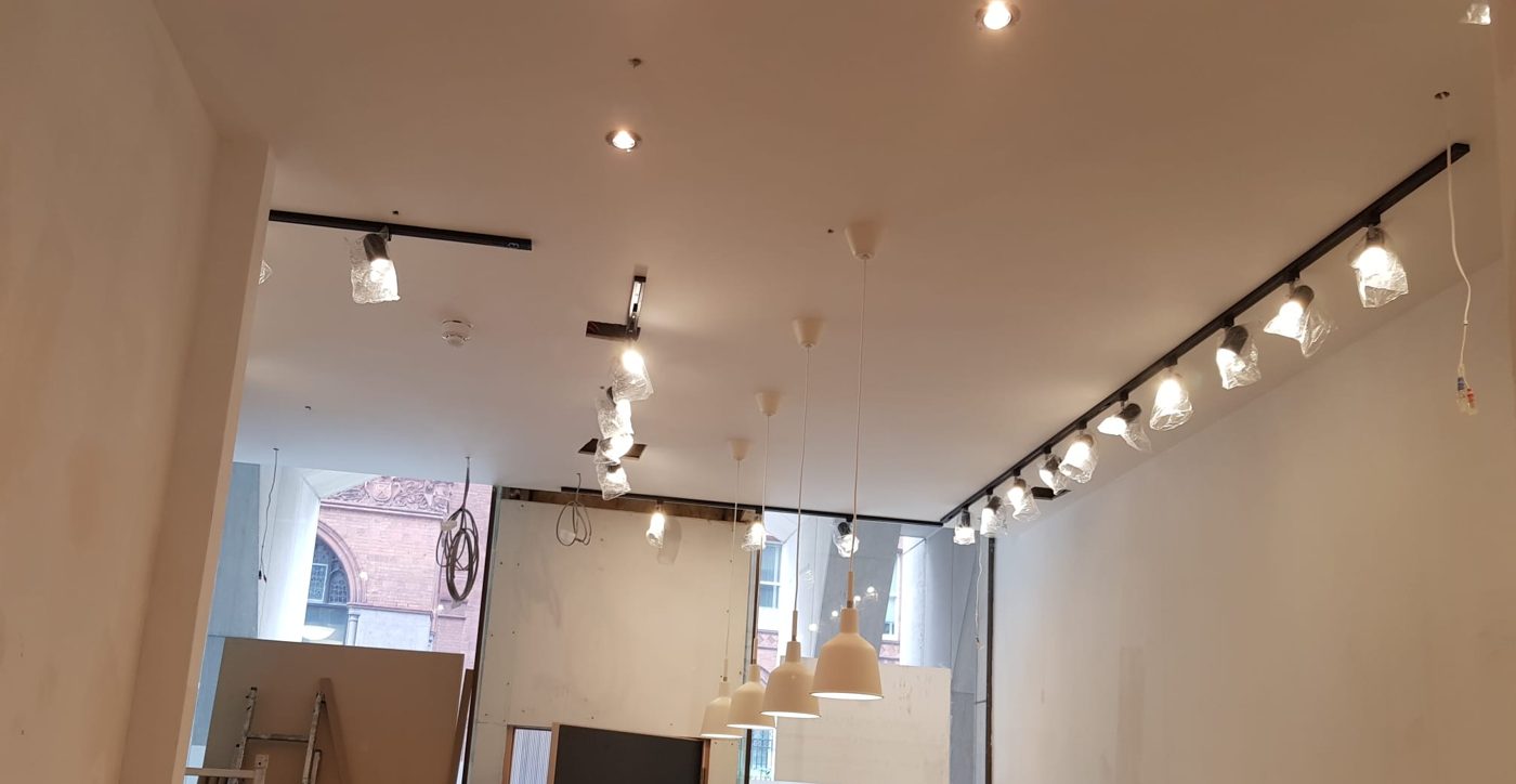 Track spotlights and recessed downlights across the shop, with pendants over the counter