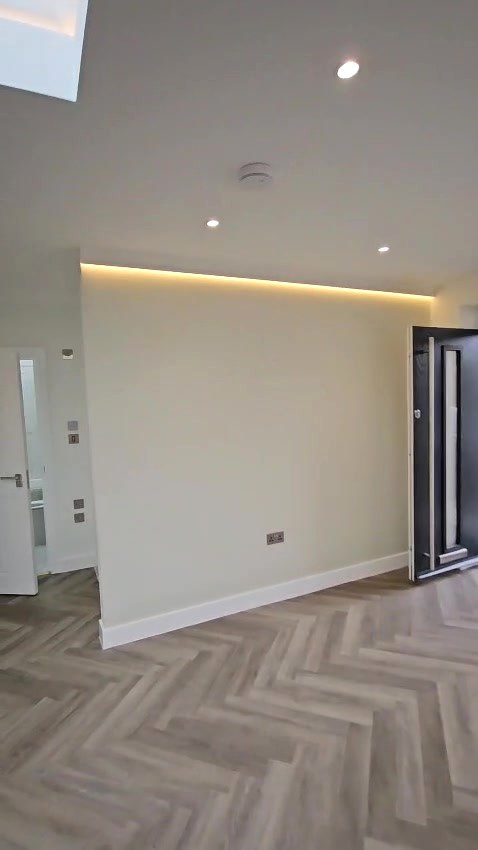 After: LED cove lighting along the ceiling line, with switches and sockets finished in brushed steel