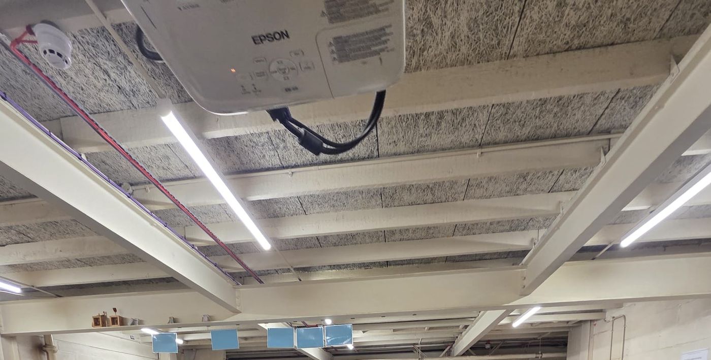 LED battens fixed between the exposed beams, clear of the ceiling projector and fire detection