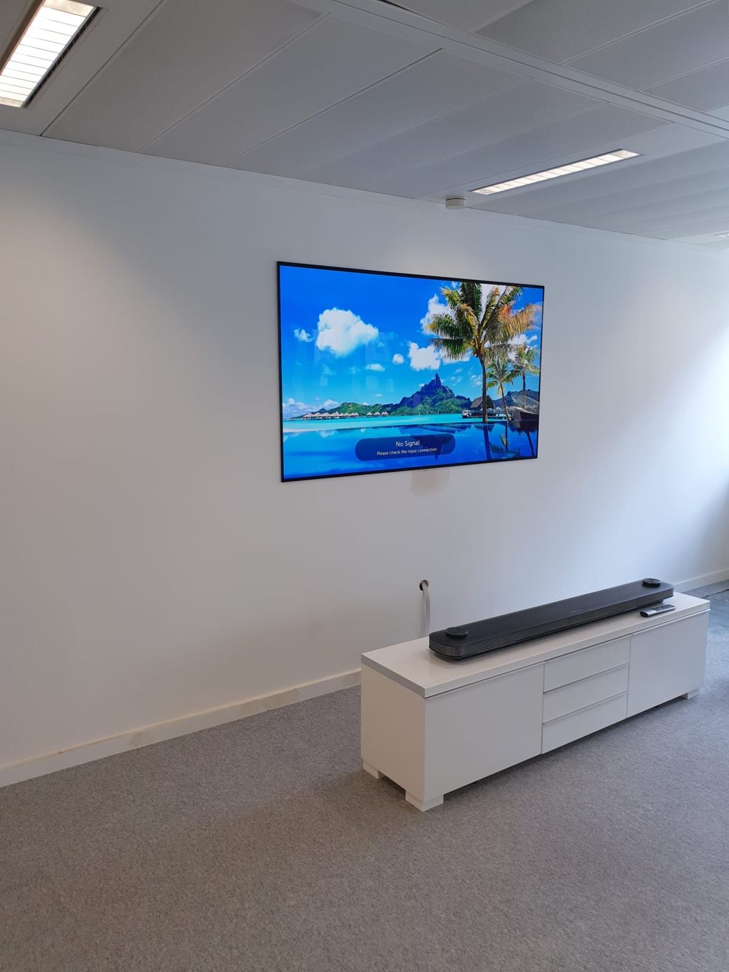 A large screen mounted flush to the wall, with power and data hidden behind it and a cable outlet down to the media unit